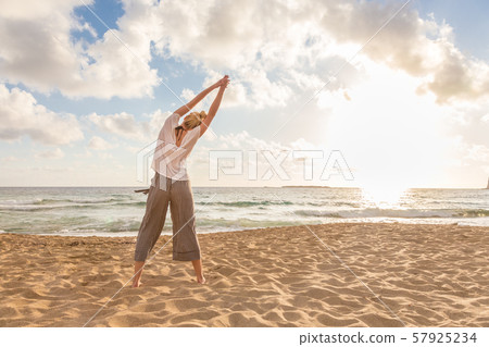 Woman practicing yoga on sea beach at sunset. Woman practicing yoga on sea beach at sunset. 57925234