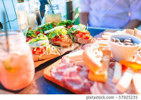 Tasty italian snack. Fresh bruschettes, cheeses and meat on the board in cafe with view in Manarola 57925235