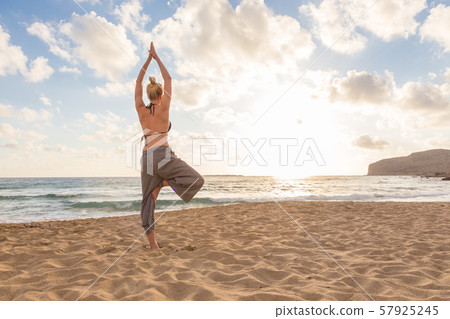 Woman practicing yoga on sea beach at sunset. Woman practicing yoga on sea beach at sunset. 57925245