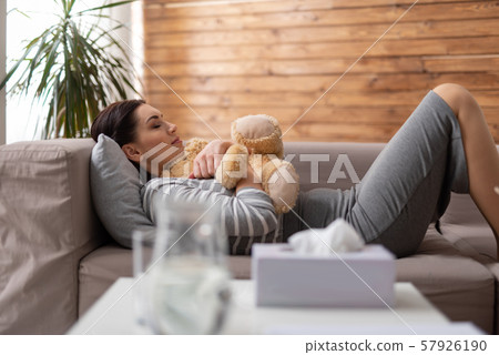 Brunette Caucasian woman lying on sofa with toy in arms 57926190