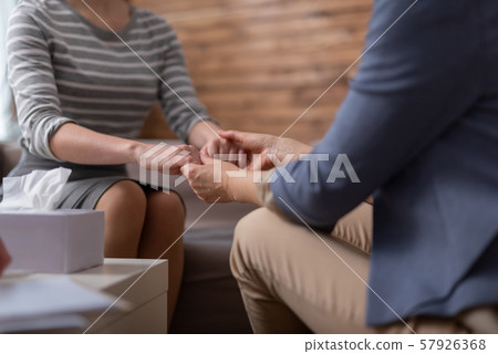 Side view of female psychologist holding client arms during seance Side view of female psychologist holding client arms during seance 57926368