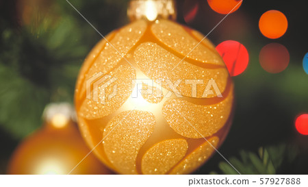 Closeup toned photo of golden baubles hanging on Christmas tree branch against glowing lights 57927888