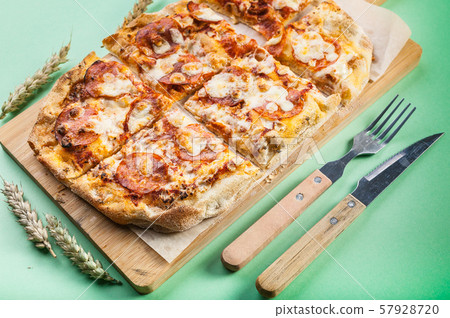 Peperroni pizza on a cutting board on a green 57928720