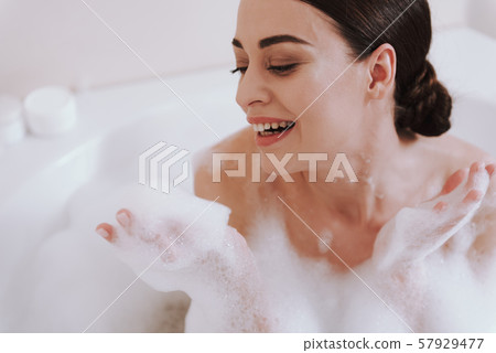 Joyful young woman enjoying her bath procedure Joyful young woman enjoying her bath procedure 57929477