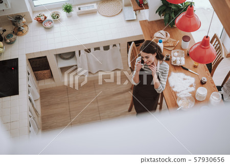 Smiling woman is talking on phone while cooking pastry Smiling woman is talking on phone while cooking pastry 57930656