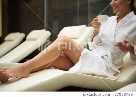 Joyful young lady with hot drink lying on comfortable daybed 57930789