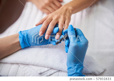 Manicurist buffing lady nails in order to make them more shiny Manicurist buffing lady nails in order to make them more shiny 57931633