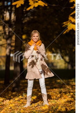 Portrait of pretty blonde teen girl having fun in autumn park near tree with yellow leaves Portrait of pretty blonde teen girl having fun in autumn park near tree with yellow leaves 57931759