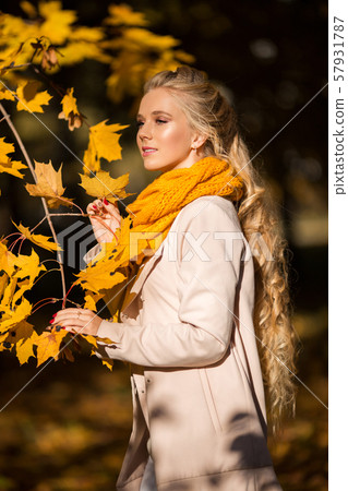 Portrait of pretty blonde teen girl with fashion makeup near autumn tree with yellow leaves 57931787