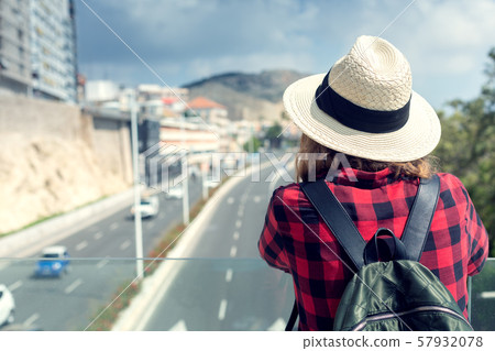 A young woman in her hat with a backpack stands on 57932078