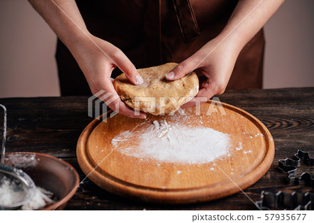 Woman kneading gingerbread dough on pastry board Woman kneading gingerbread dough on pastry board 57935677
