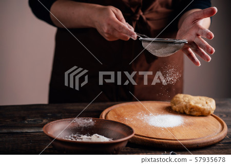 Woman sprinkling flour on gingerbread dough Woman sprinkling flour on gingerbread dough 57935678