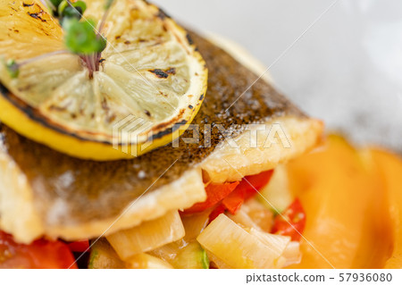 Roasted pike perch or cod fish with baked vegetables. Dish decorated with a slice of lemon 57936080