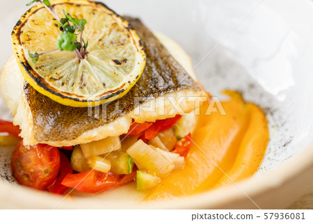 Roasted pike perch or cod fish with baked vegetables. Dish decorated with a slice of lemon 57936081