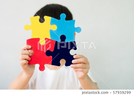 Close up studio portrait : A little child holding a puzzle symbol of Public awareness for autism spectrum disorder. World Autism Awareness Day, Caring, Speak out, Campaign, Togetherness. Isolated. 57939299