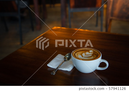 Hot art Latte Coffee in a cup on wooden table and Coffee shop blur background Hot art Latte Coffee in a cup on wooden table and Coffee shop blur background 57941126