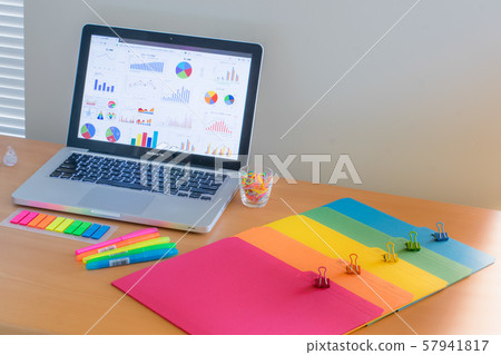 Laptop and colorful stationery displaying graphs 57941817