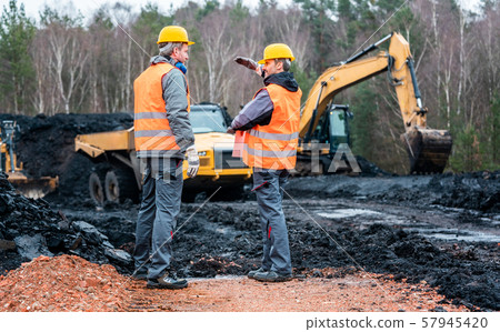 Two quarry workers discussing what to do next 57945420