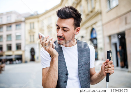 Young blind man with smartphone on street in city, making phone call. Young blind man with smartphone on street in city, making phone call. 57945675