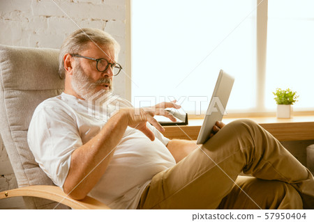 Senior man working with tablet at home - concept of home studying 57950404
