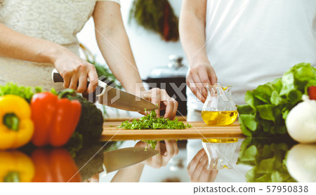 Closeup of human hands cooking in kitchen. Mother and daughter or two female friends cutting Closeup of human hands cooking in kitchen. Mother and daughter or two female friends cutting 57950838