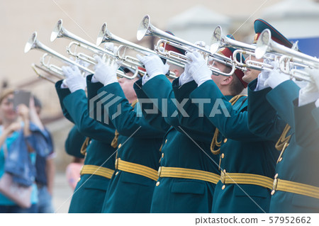 A wind instrument parade - men in green official costumes with yellow belts playing trumpets A wind instrument parade - men in green official costumes with yellow belts playing trumpets 57952662
