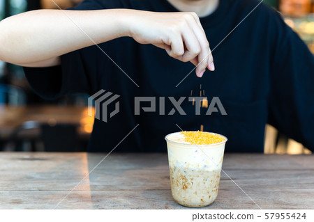 Barista making iced milk tea with salty egg at cafe. 57955424