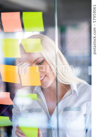 business, startup, planning, management and people concept - happy woman writing on stickers at business, startup, planning, management and people concept - happy woman writing on stickers at 57959061