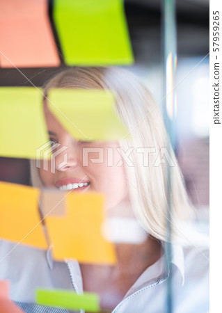 business, startup, planning, management and people concept - happy woman writing on stickers at 57959265