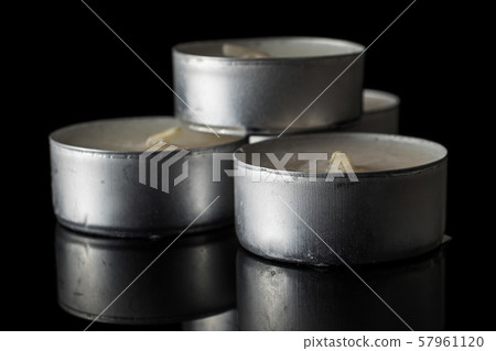 Waxy tea candle isolated on black glass Waxy tea candle isolated on black glass 57961120