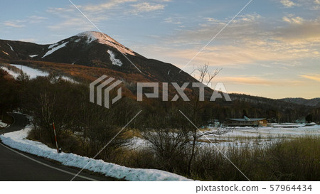 A small snow capped mountain, by a frozen lake 57964434