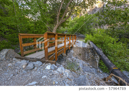 Wooden bridge over rocky stream in the wilderness 57964789