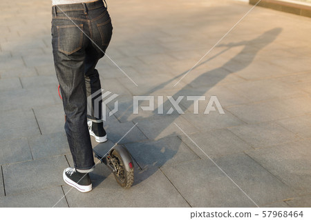 Girl riding an eco-friendly electric kick scooter in a park in sunny weather on sidewalks 57968464