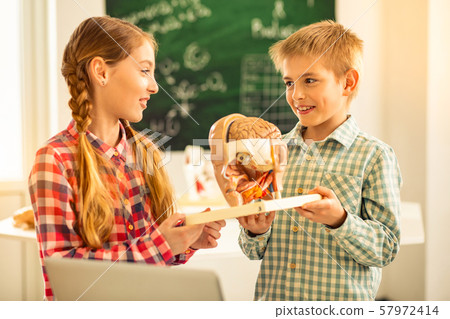 Pleased blonde girl looking at her classmate Pleased blonde girl looking at her classmate 57972414