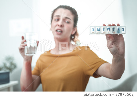 Woman holding glass of water and pills to treat allergy 57973502