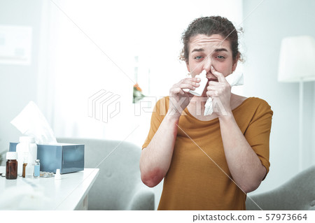 Curly woman wearing orange shirt using nose spray having allergy Curly woman wearing orange shirt using nose spray having allergy 57973664