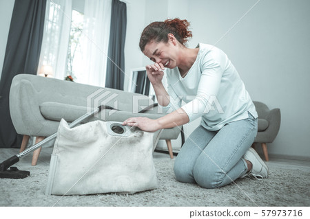 Housewife sitting on floor and sneezing having allergy to dust Housewife sitting on floor and sneezing having allergy to dust 57973716