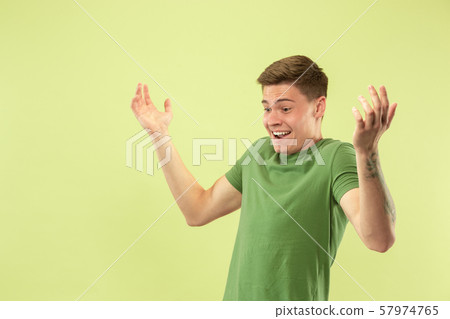 Caucasian young man's half-length portrait on green background Caucasian young man's half-length portrait on green background 57974765