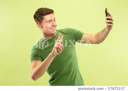 Caucasian young man's half-length portrait on green background 57975157