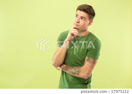 Caucasian young man's half-length portrait on green background Caucasian young man's half-length portrait on green background 57975222