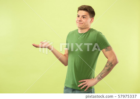 Caucasian young man's half-length portrait on green background 57975337