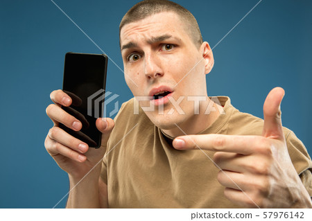 Caucasian young man's half-length portrait on blue background Caucasian young man's half-length portrait on blue background 57976142