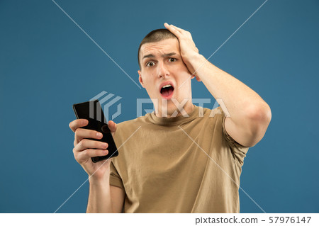 Caucasian young man's half-length portrait on blue background 57976147