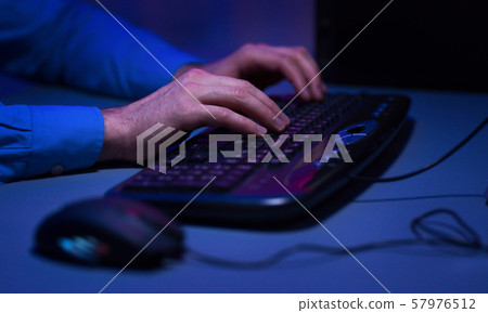 Gamer actively pushing buttons on keyboard, playing games 57976512