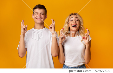Guy and girl crossing fingers with closed eyes 57977890
