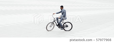 Businessman riding bicycle to work in city center 57977908