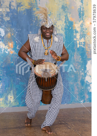 African artist in traditional clothes playing djembe drum African artist in traditional clothes playing djembe drum 57978639