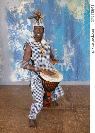 African artist in traditional clothes playing djembe drum African artist in traditional clothes playing djembe drum 57978641