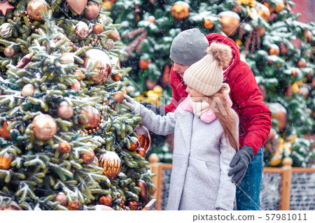 Little happy girl near fir-tree branch in snow for new year. 57981011