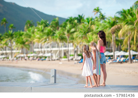 Adorable little girls and young mother on white beach in luxury resort Adorable little girls and young mother on white beach in luxury resort 57981436